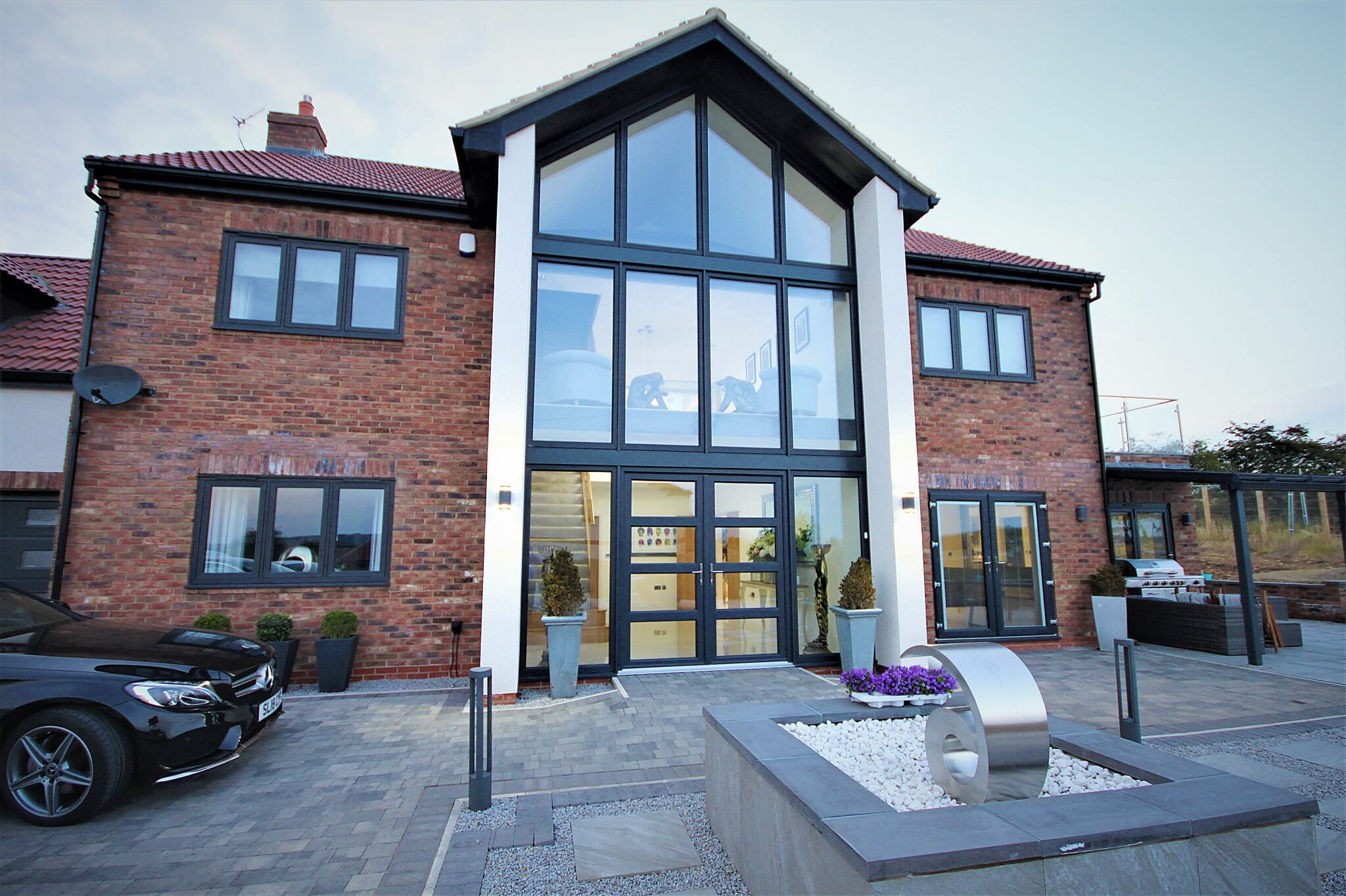 Detached brick house with a full height glazed gable and anthracite windows
