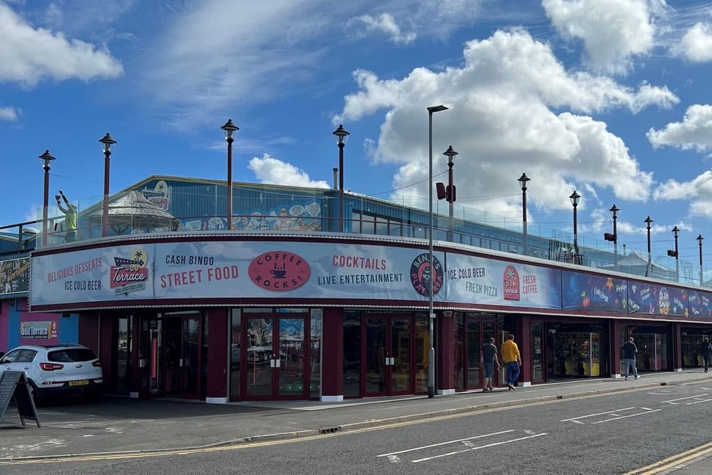 Amusement arcade frontage with a long run of dark red glazed shop fronts