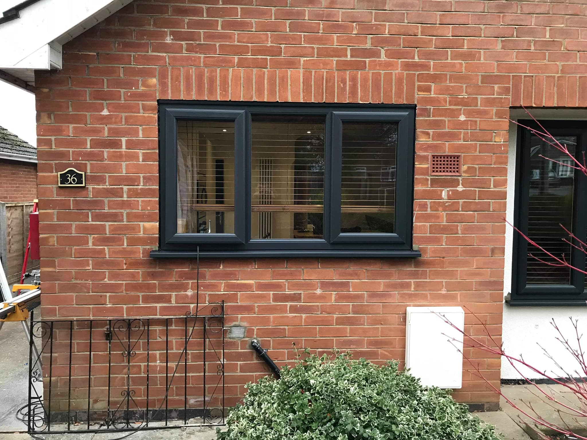 Anthracite grey three pane casement window on a red brick house