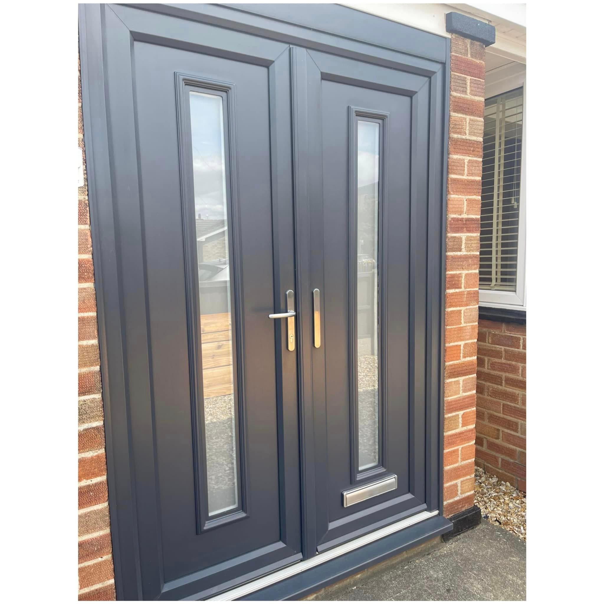 Pair of anthracite grey entrance doors with tall narrow glazed panels in a brick surround