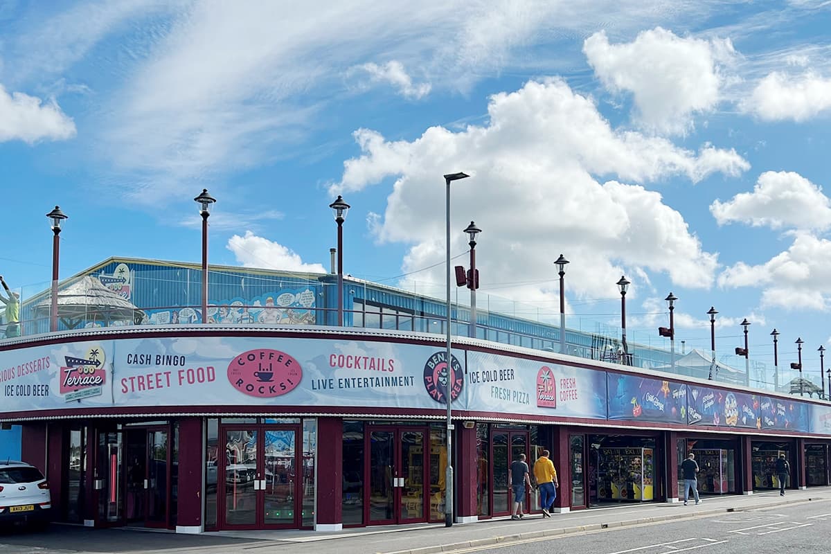 Curved corner shop front with dark red glazed units and banner signage above