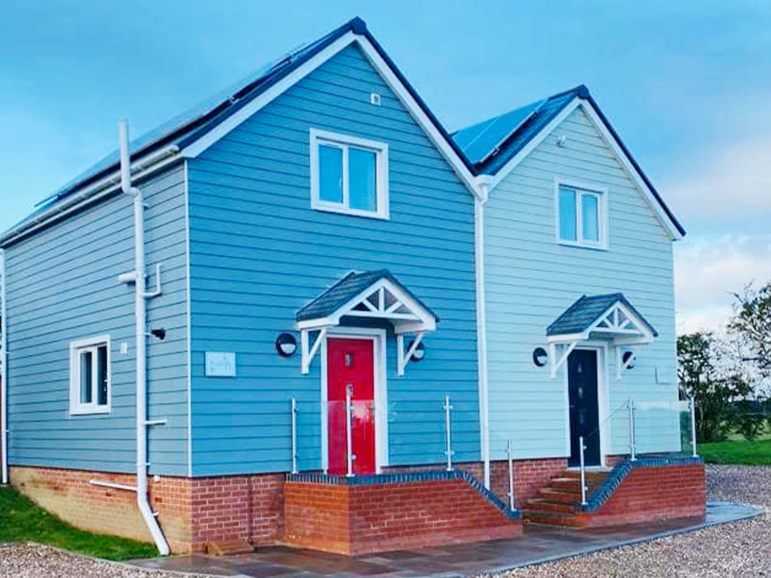 Pair of blue and pale grey clad houses with white windows and porch canopies