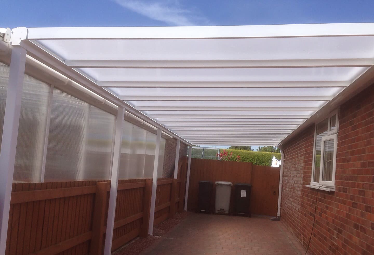 Translucent roofed canopy running the length of a block paved side run on the day it was fitted