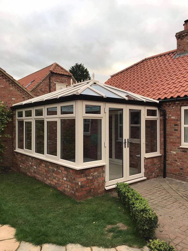 Cream conservatory with a glazed hipped roof and French doors onto a patio