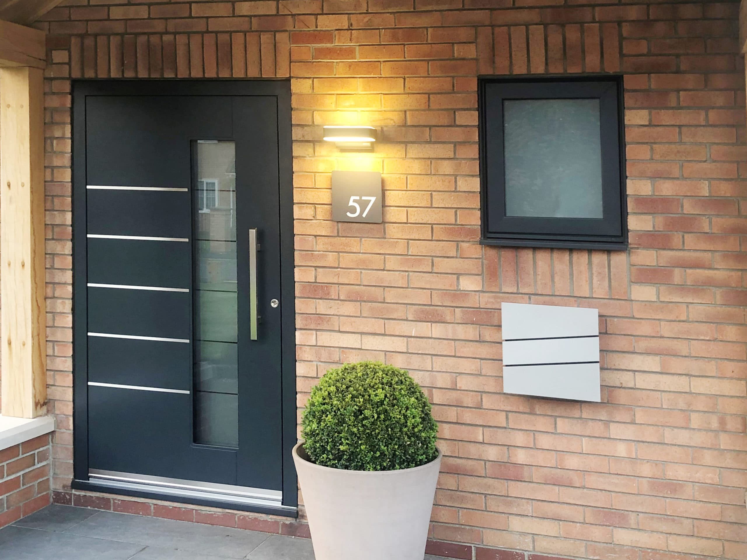 Dark grey front door with brushed steel inlays and long bar handle