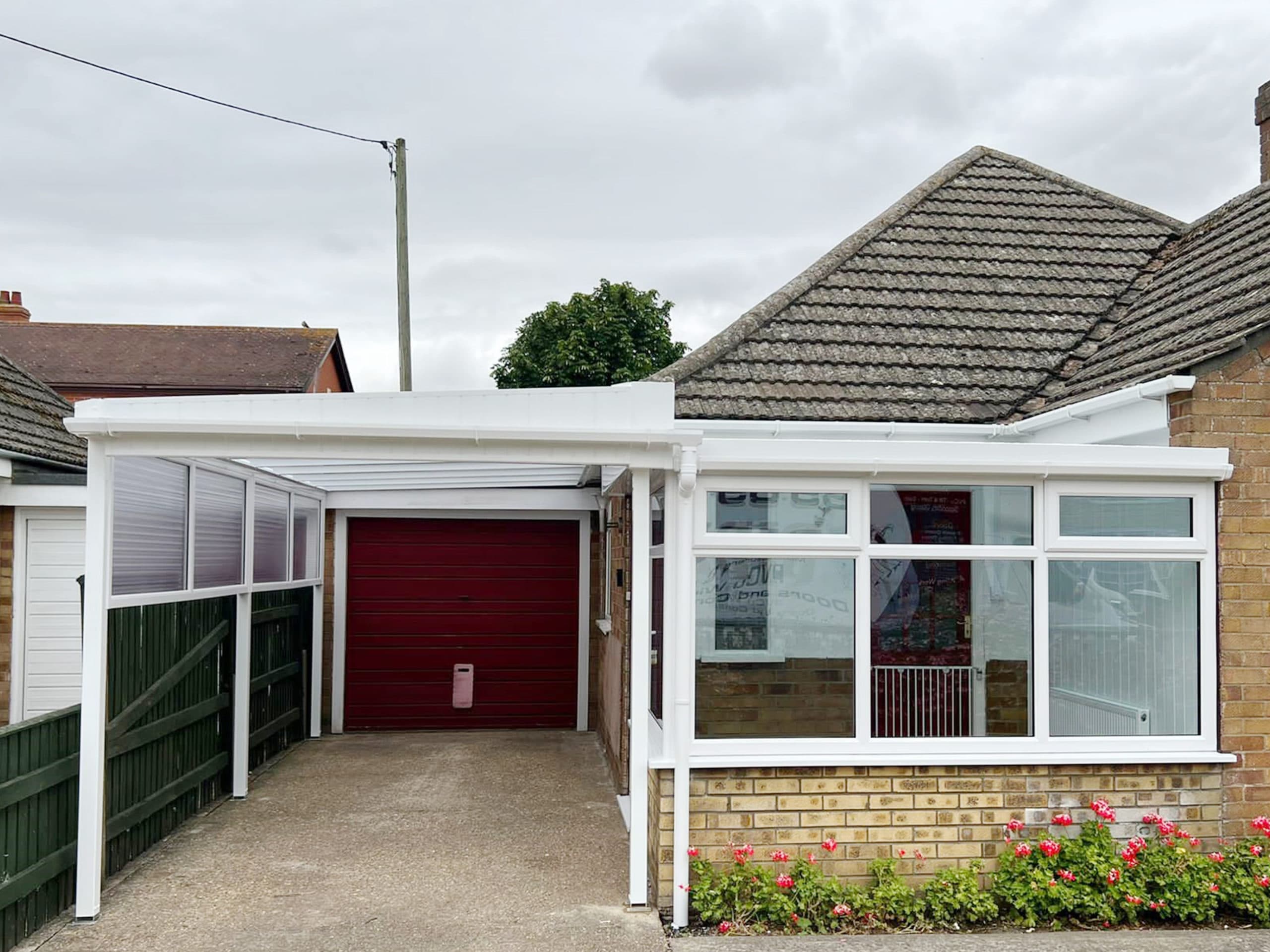 White carport canopy running to a glazed lean-to sunroom on a brick bungalow