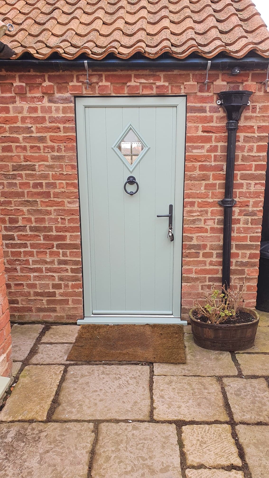 Sage green cottage style door with a diamond glazed light and black ring knocker