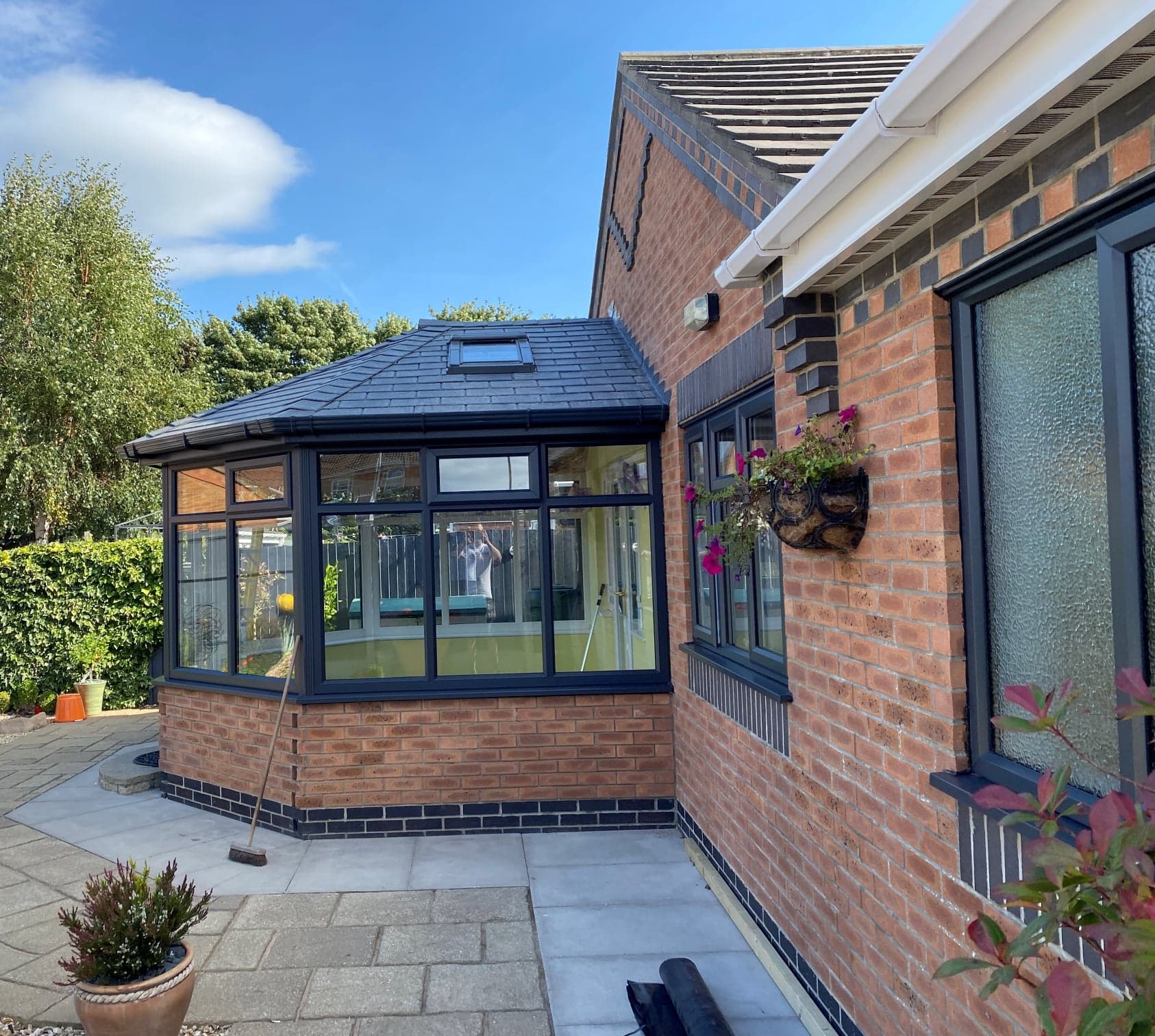 Anthracite grey conservatory with a solid tiled roof and roof window on a brick house
