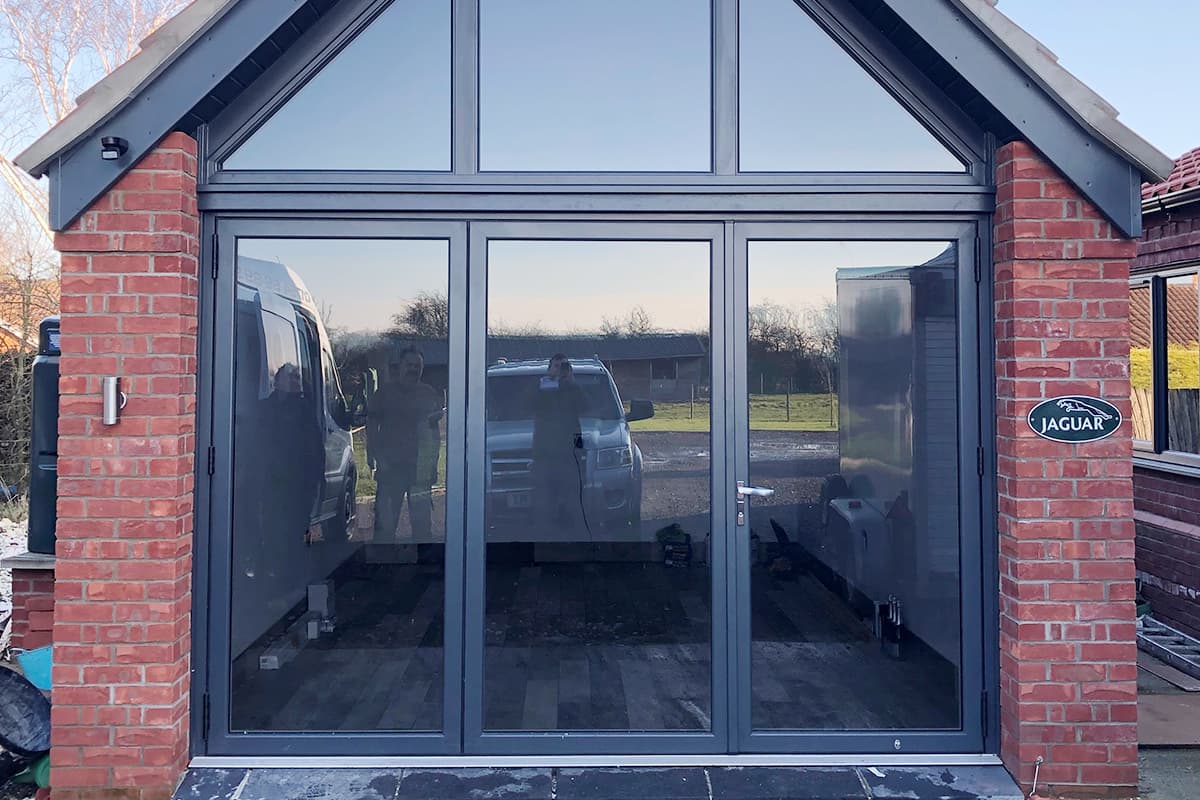 Dark grey glazed doors and apex glazing filling a brick gable end