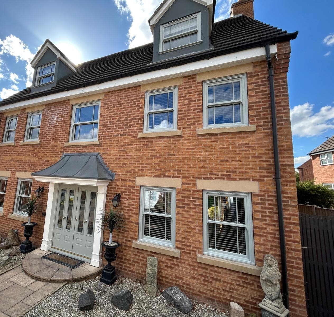 Light grey sliding sash windows and matching double front doors on a red brick house