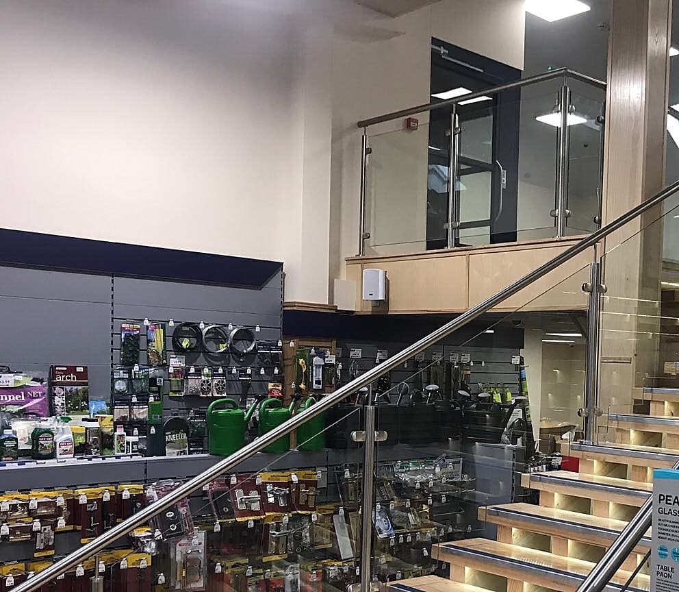 Glass balustrade on a shop landing above a lit timber staircase