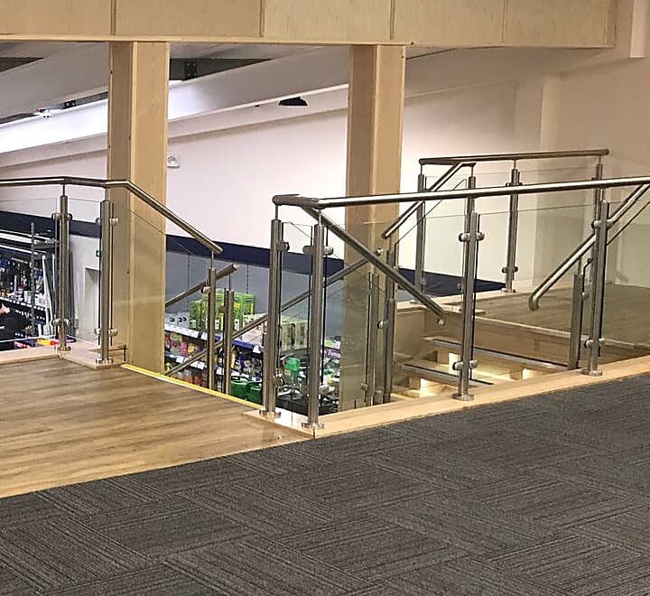 Glass and stainless balustrade at the head of a staircase inside a shop
