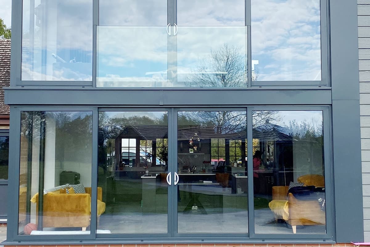 Two storey grey framed glazed screen with central opening doors on each floor