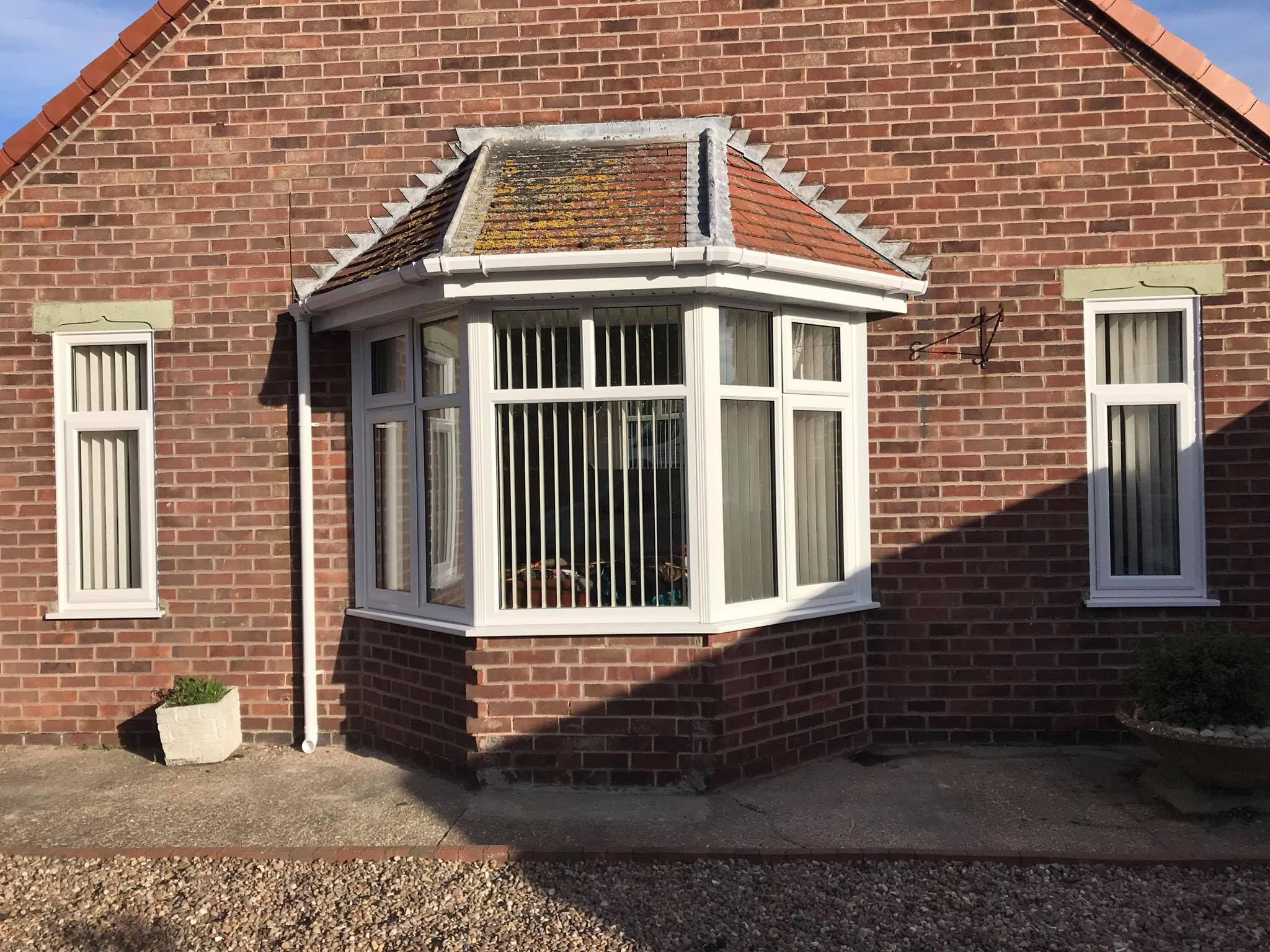 White bay window with tiled roof on a red brick bungalow