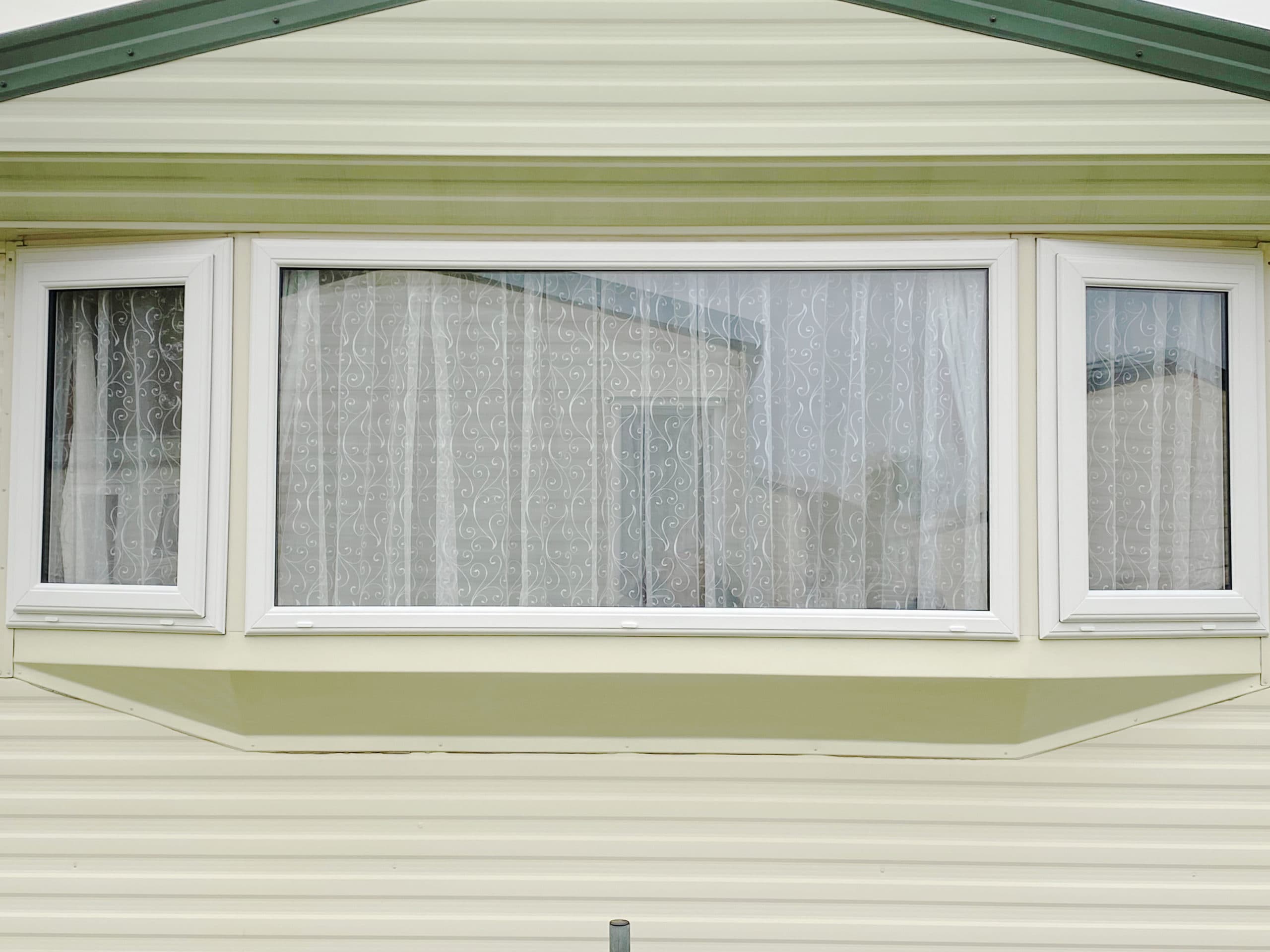 White framed bay window with side opening casements on cream clad building