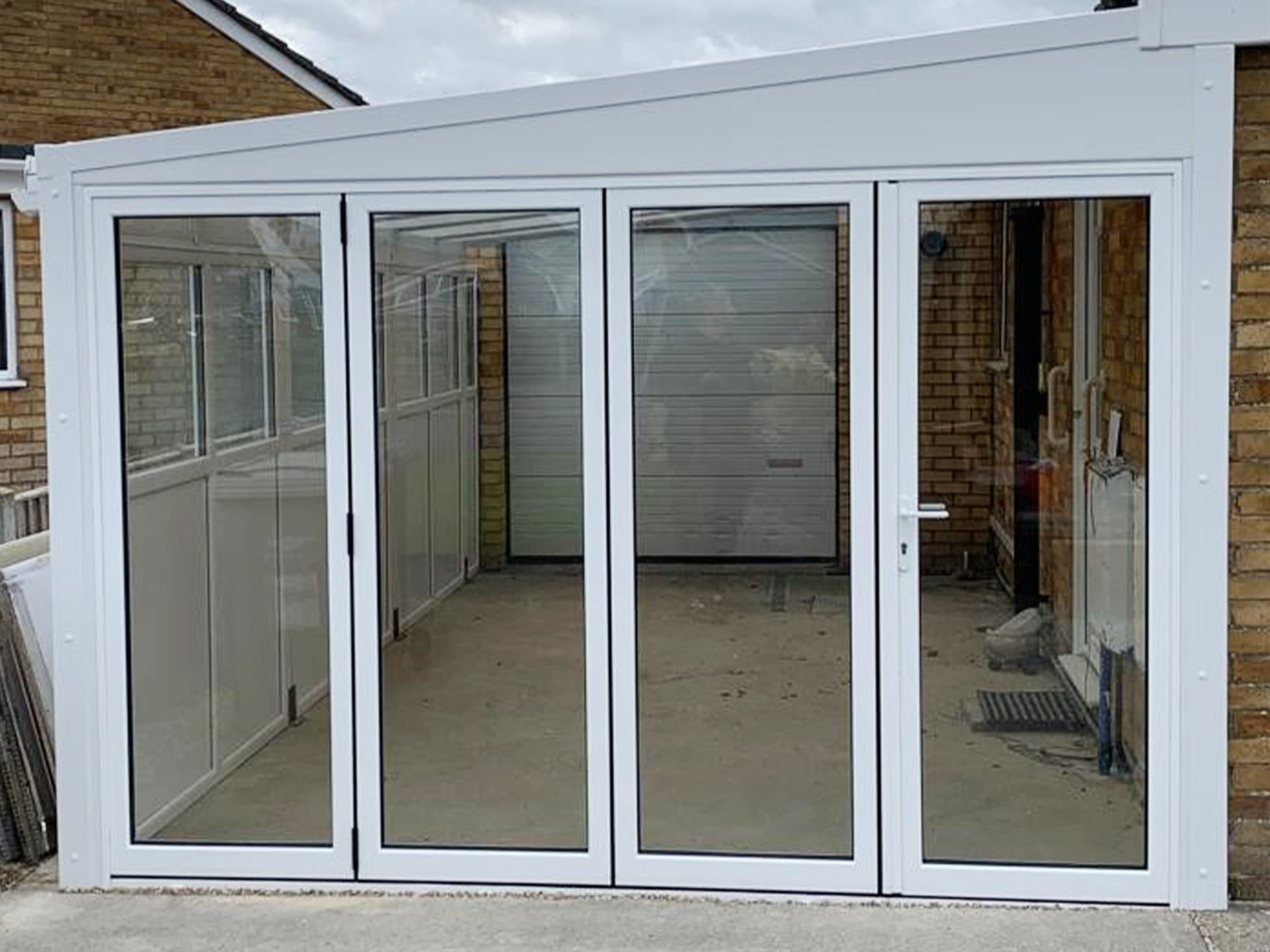 White four leaf bifolding doors closing a lean to between pale brick walls