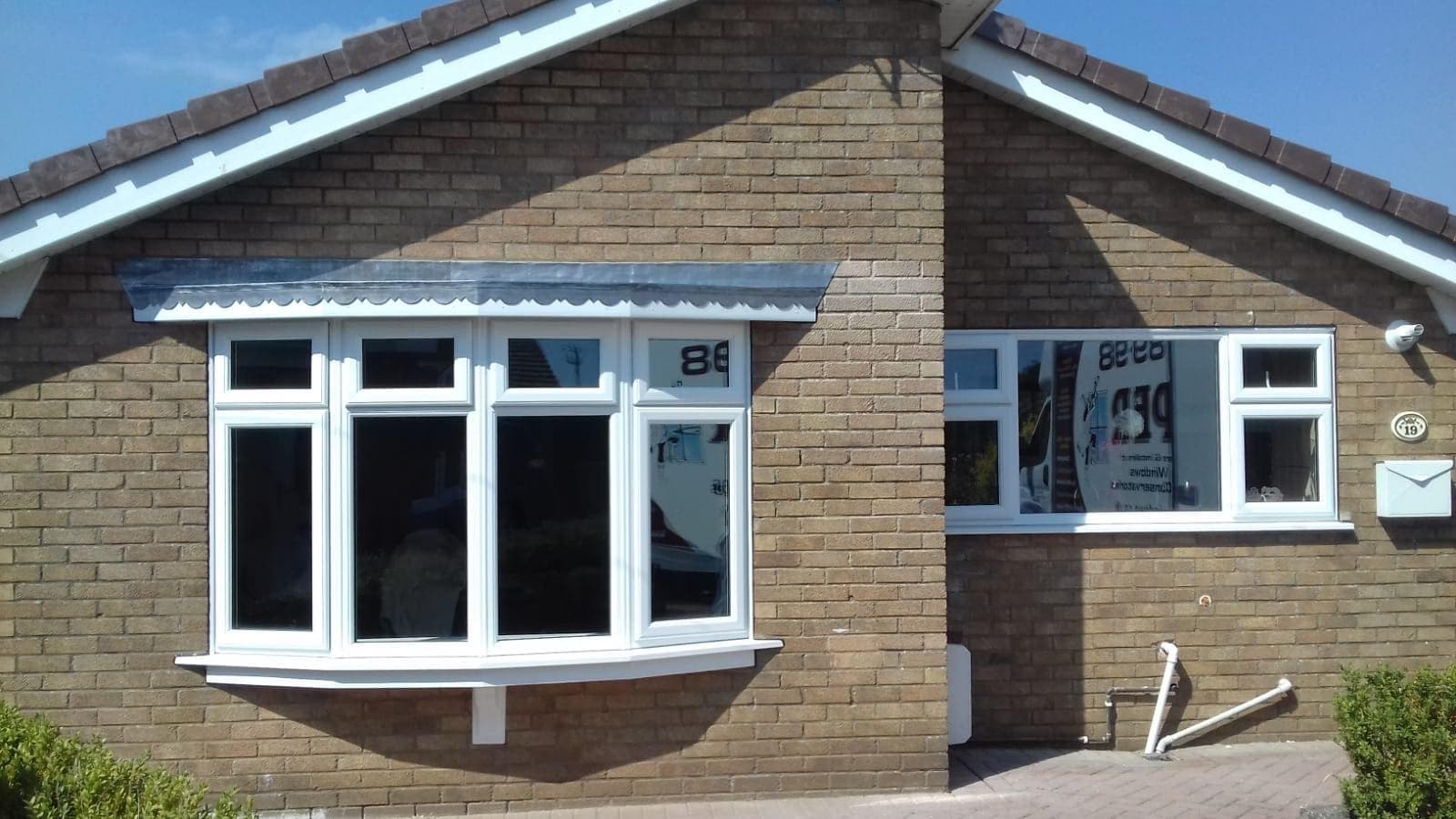 White four light bow window under a grey canopy on a brick bungalow