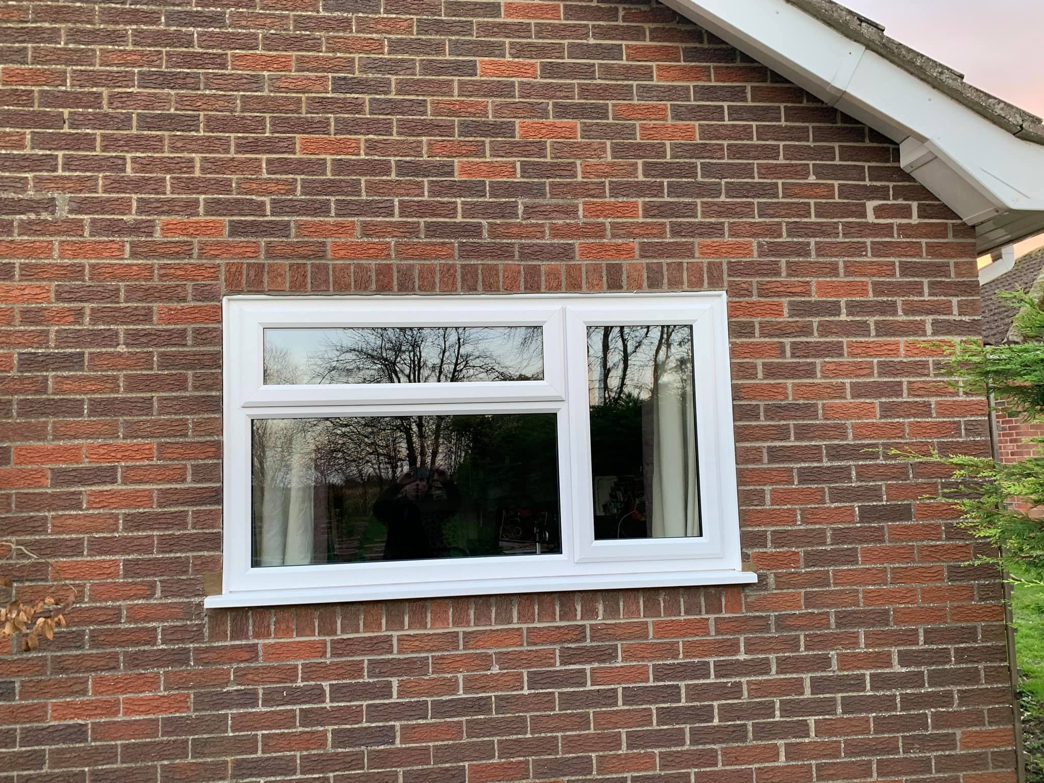 White casement window with top opening vent in a brick wall