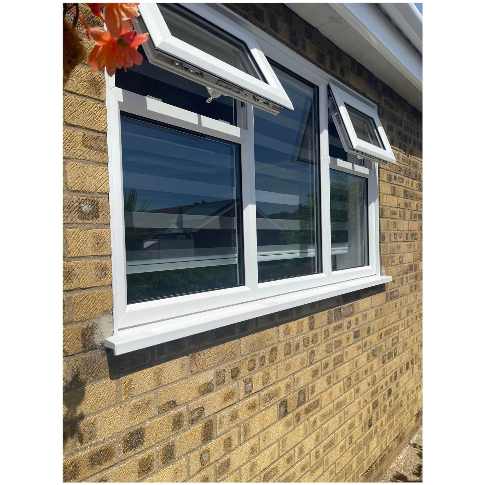 White casement window with two top vents standing open in buff brickwork