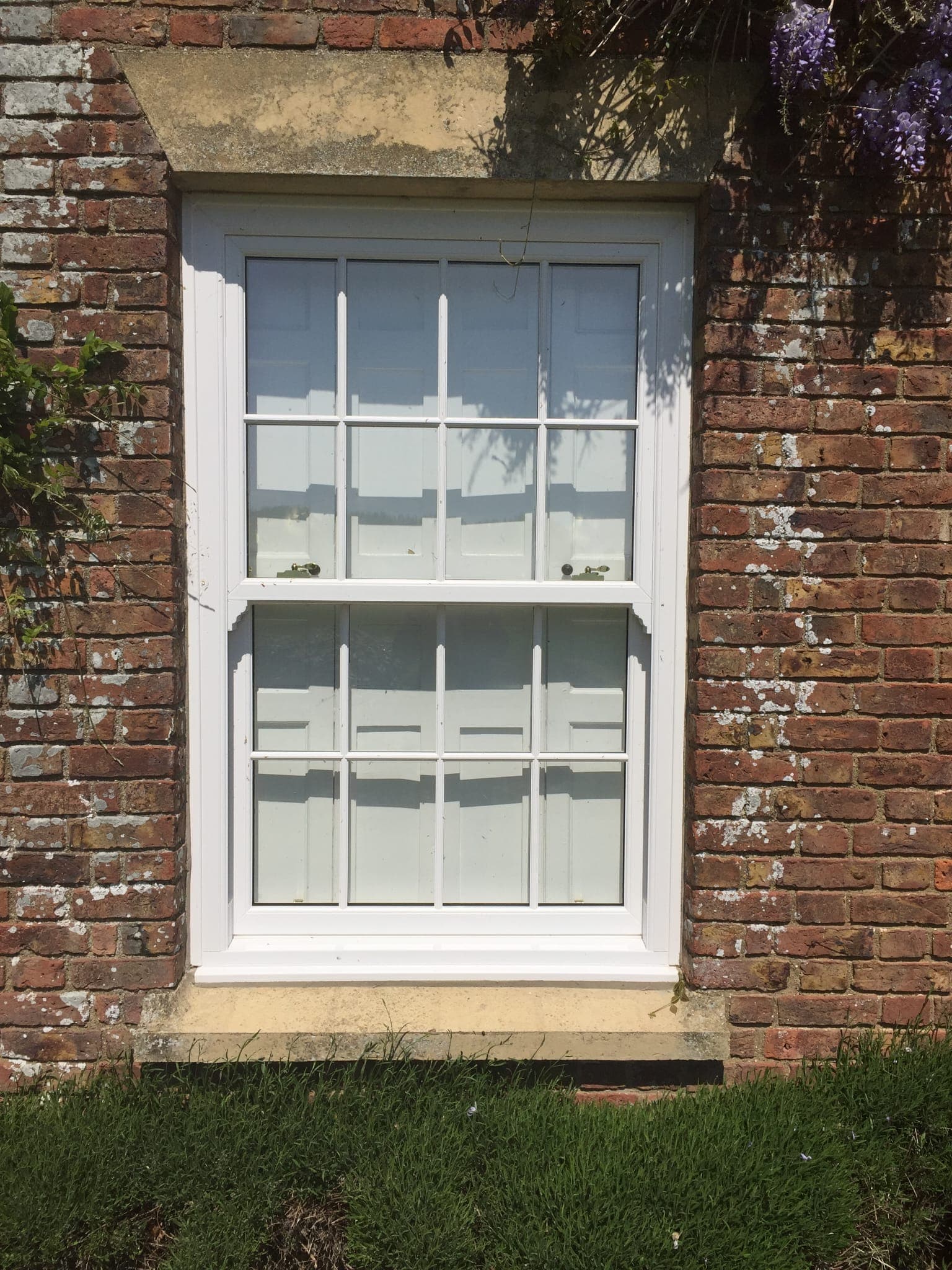 White sliding sash window with Georgian glazing bars in a weathered red brick wall