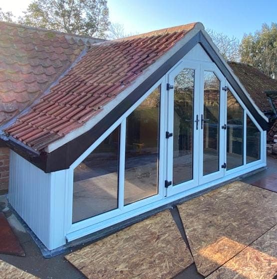 White French doors with shaped side panes in a glazed gable end under a pantile roof