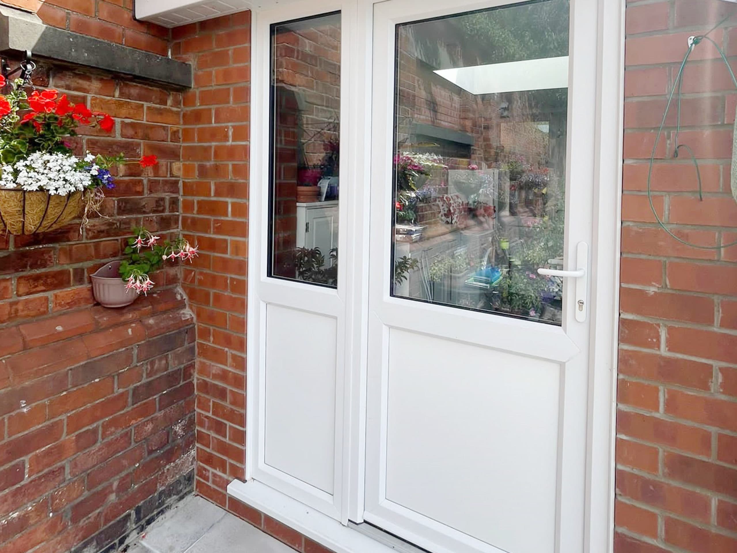White half glazed door and matching panel in a brick opening with hanging baskets