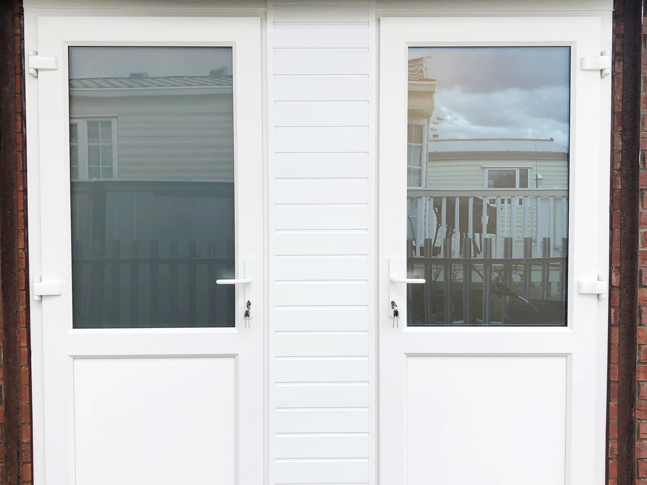 Two white half glazed doors either side of a ribbed white infill panel