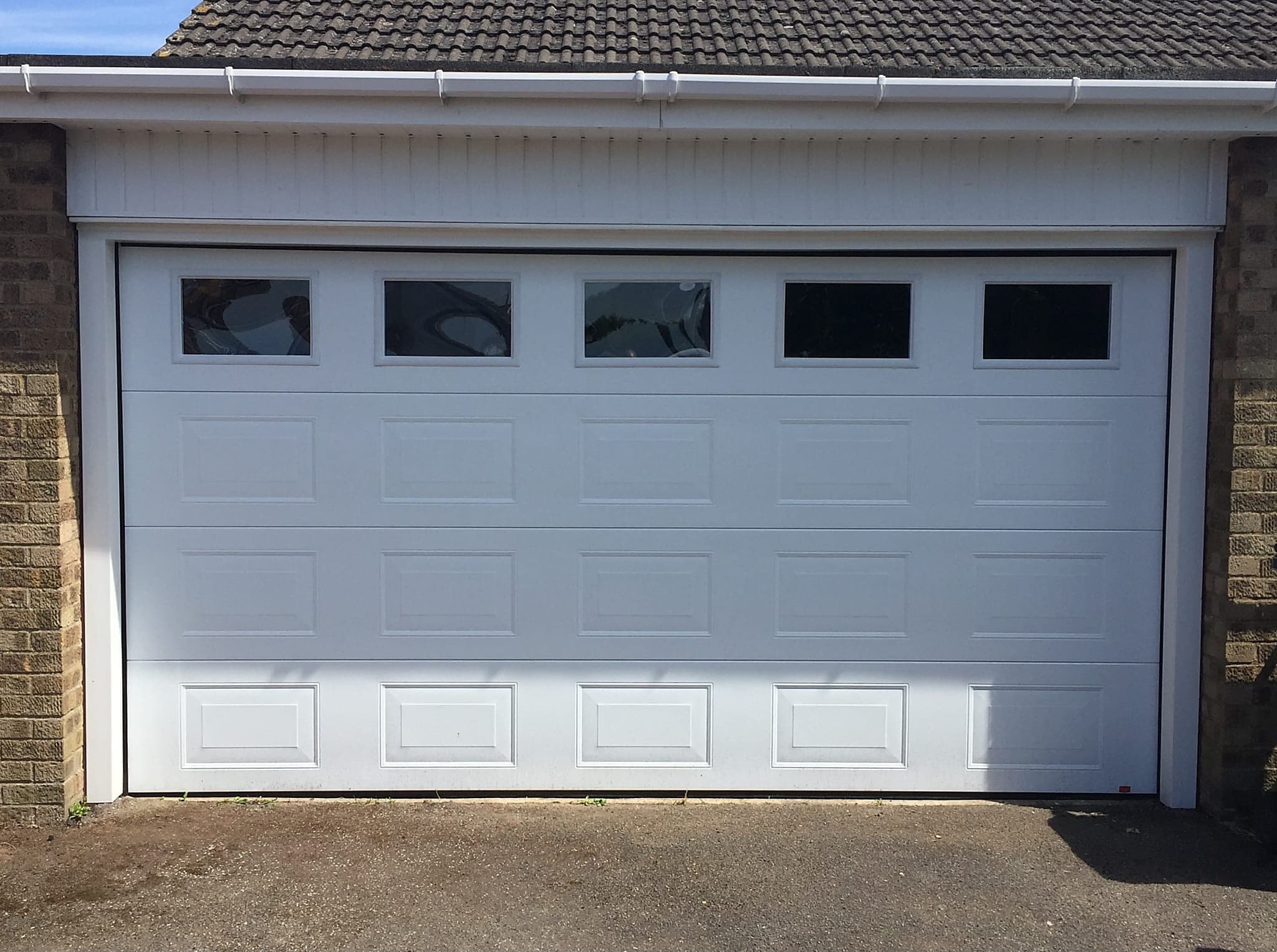 White panelled garage door with five glazed panes across the top
