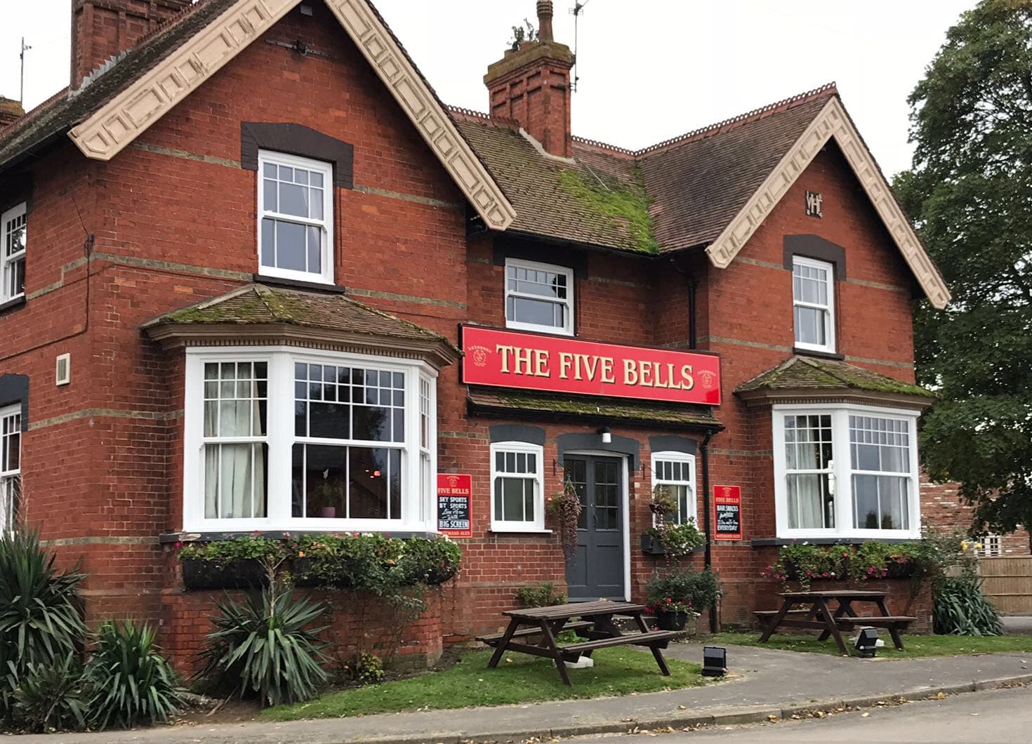 White sliding sash windows with glazing bars, including two canted bay windows, across a red brick pub frontage