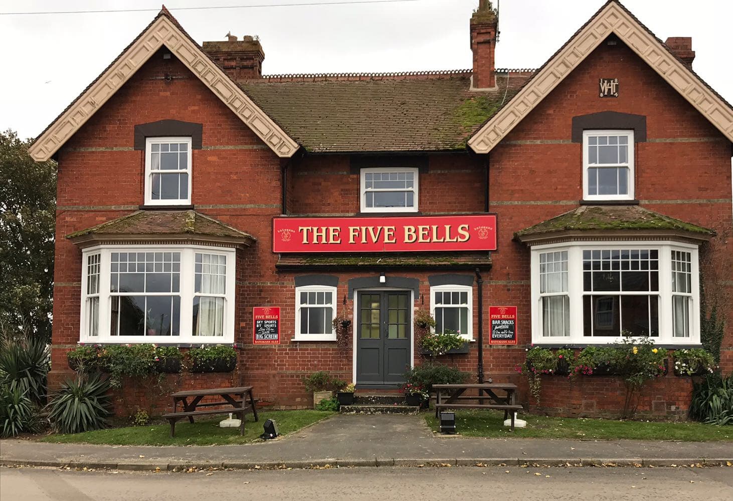 White sliding sash windows with glazing bars and two bay windows across a red brick pub frontage