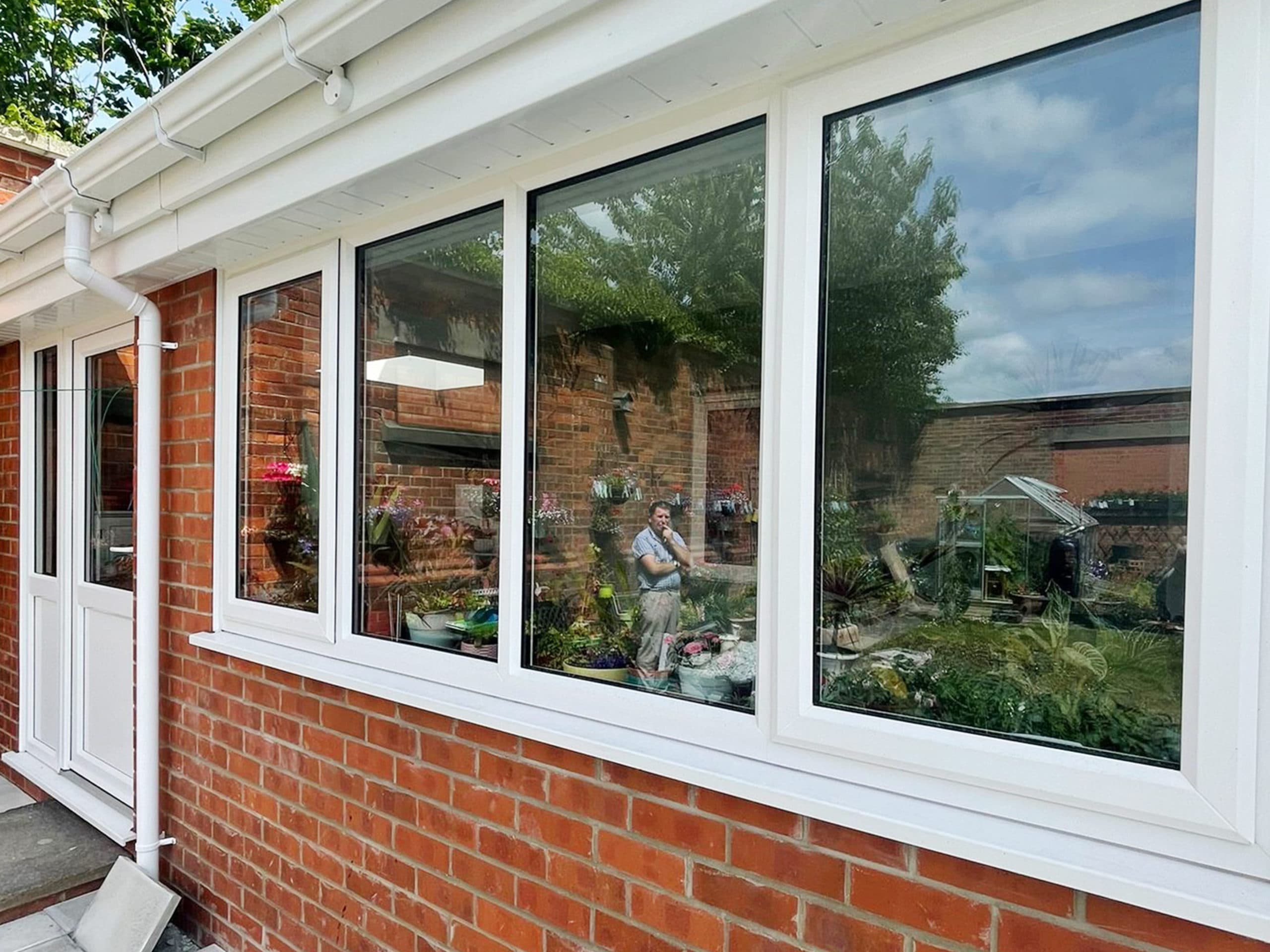 Run of white framed windows above red brick with matching white fascia and guttering