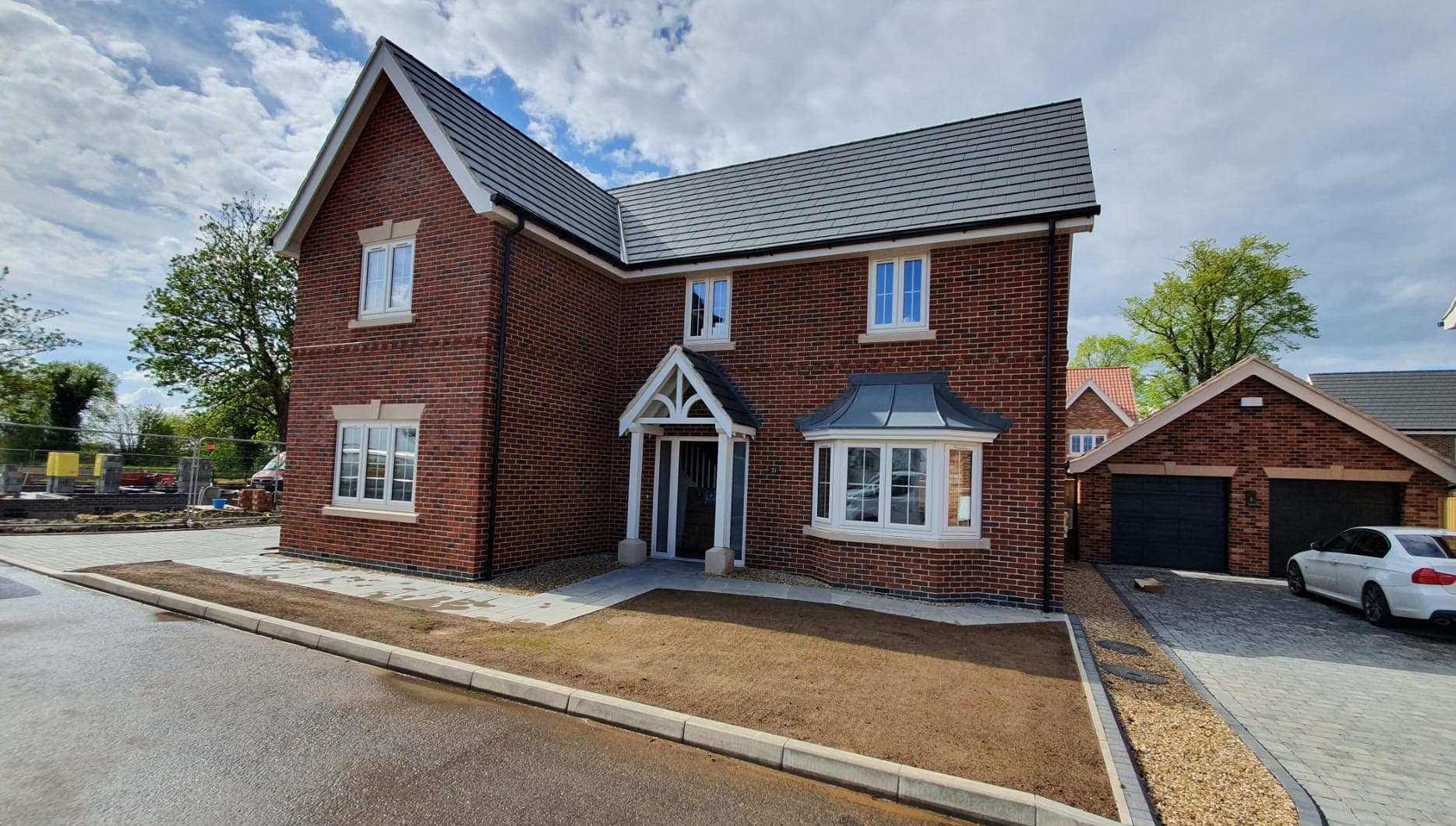 Red brick house with white windows and a three sided bay window under a grey canopy