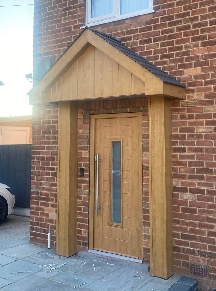 Woodgrain effect front door with slim glazed panel under a gabled porch canopy